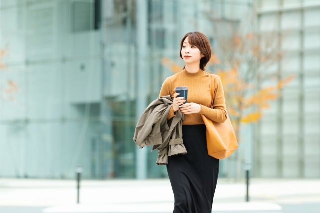 秋のオフィス街を歩く女性