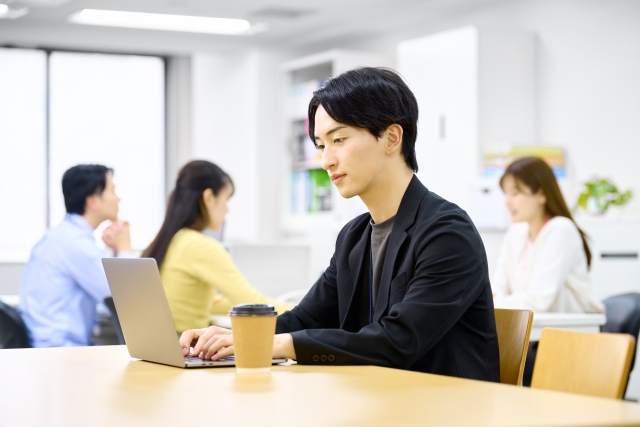コーヒーとともにパソコンでしごとをする若い男性